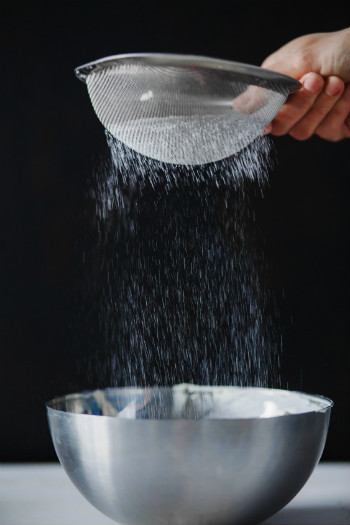 An image of flour being sifted into a bowl